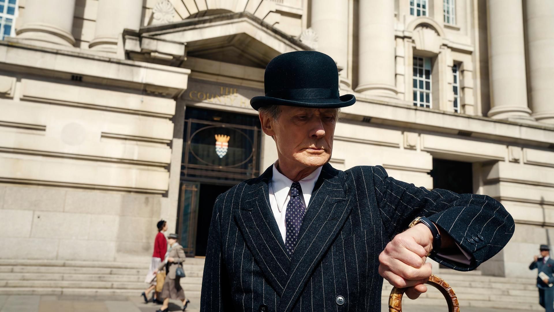 Bill Nighy mirando su reloj en la película Vivir 