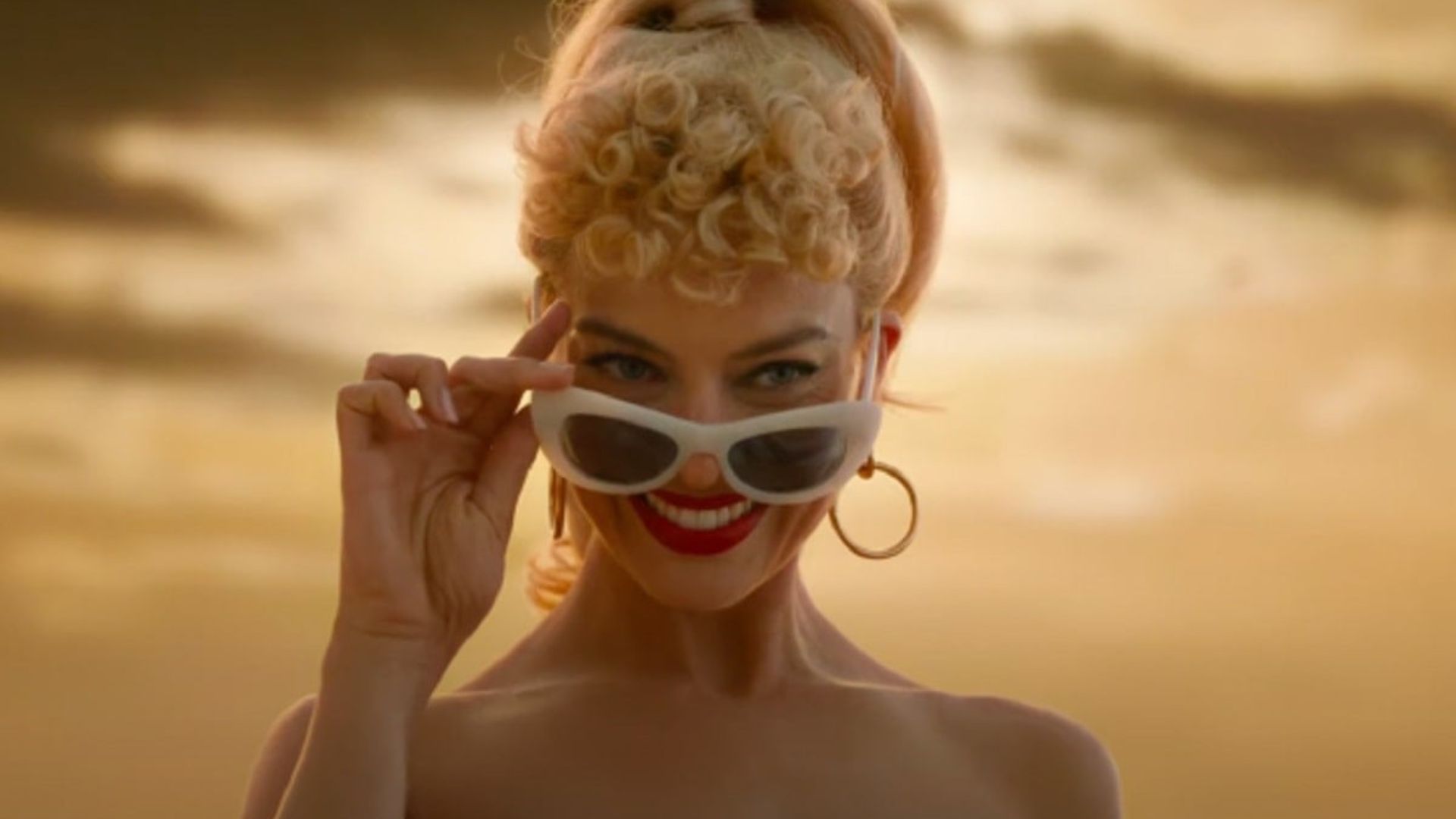 margot robbie sonriendo con lentes en escena de barbie