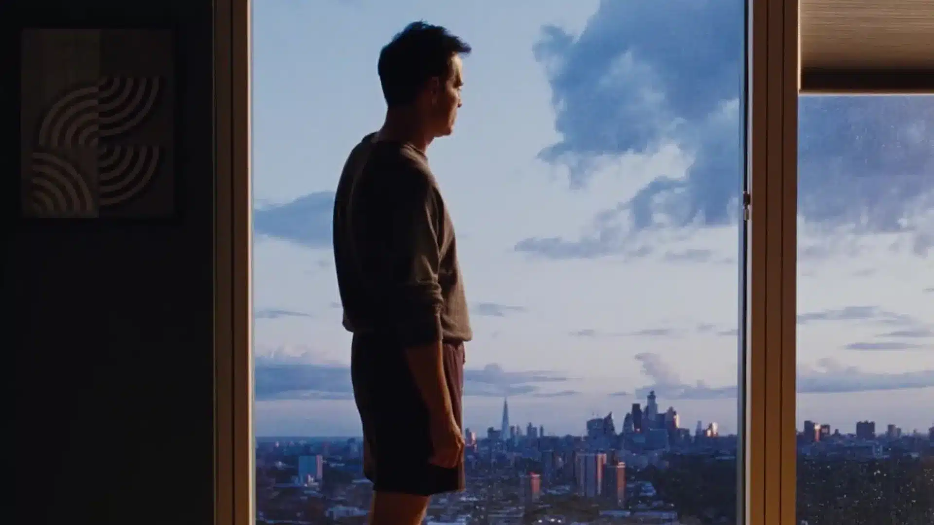 Adam Scott mirando desde la ventana de su edificio en All of us Strangers