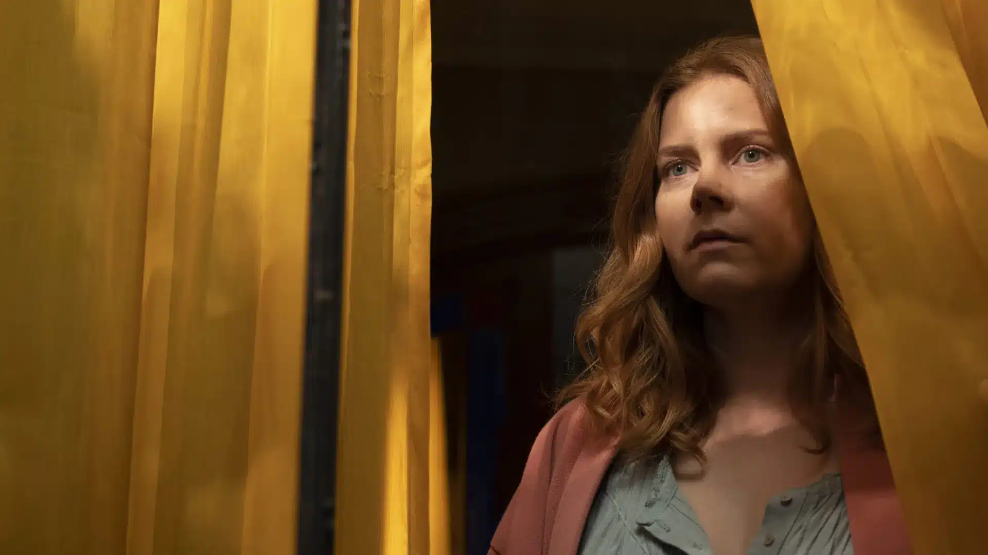 Amy Adams viendo a través de una ventana con cara de frustración.