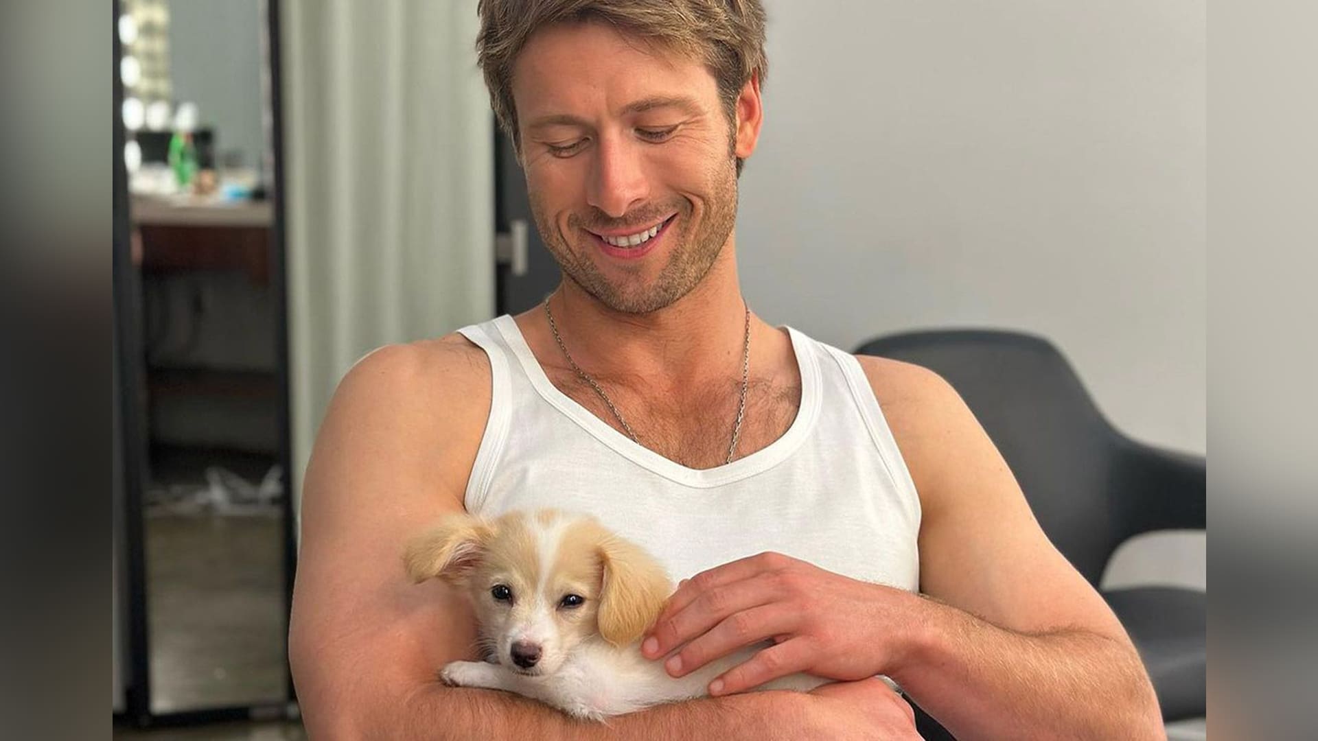 Glen Powell acariciando a su perrito